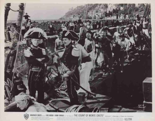 Black-and-white still from The Count of Monte Cristo showing sailors and guards on a ship deck, with two officers in ornate 18th‑century uniforms in the foreground.