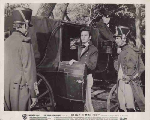 Man in formal coat steps from a dark carriage guarded by soldiers in period uniform.