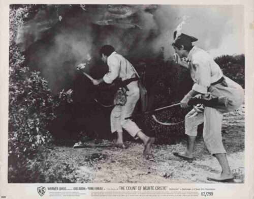 Black-and-white film still from The Count of Monte Cristo: two men in 18th‑century costumes running through smoke toward a hedge, one with a pistol.