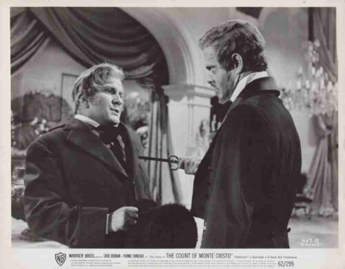 Promotional still from The Count of Monte Cristo: two men in 19th-century dress in a tense confrontation, a sword pointed toward the other.