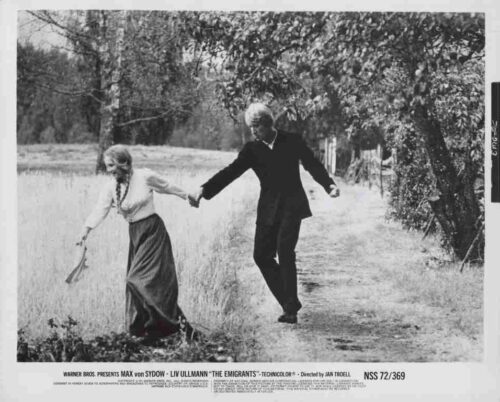 Vintage film still of an elderly couple walking hand in hand along a rural dirt path, black-and-white image.