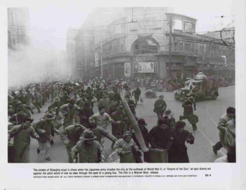 Chaotic city street as soldiers and civilians flee during wartime Shanghai invasion scene (smoke in the air).