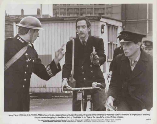 Black-and-white scene of Henry Faber showing papers to a uniformed security guard at the entrance to Waterloo Station, with another guard on a bicycle watching nearby.
