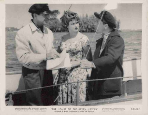 Promotional still from The House of the Seven Hawks: three people on a boat deck examining a map.