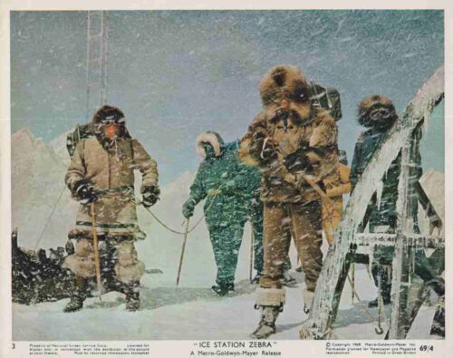 Researchers in heavy winter gear stand on snow outside an ice station labeled 'Ice Station Zebra'.