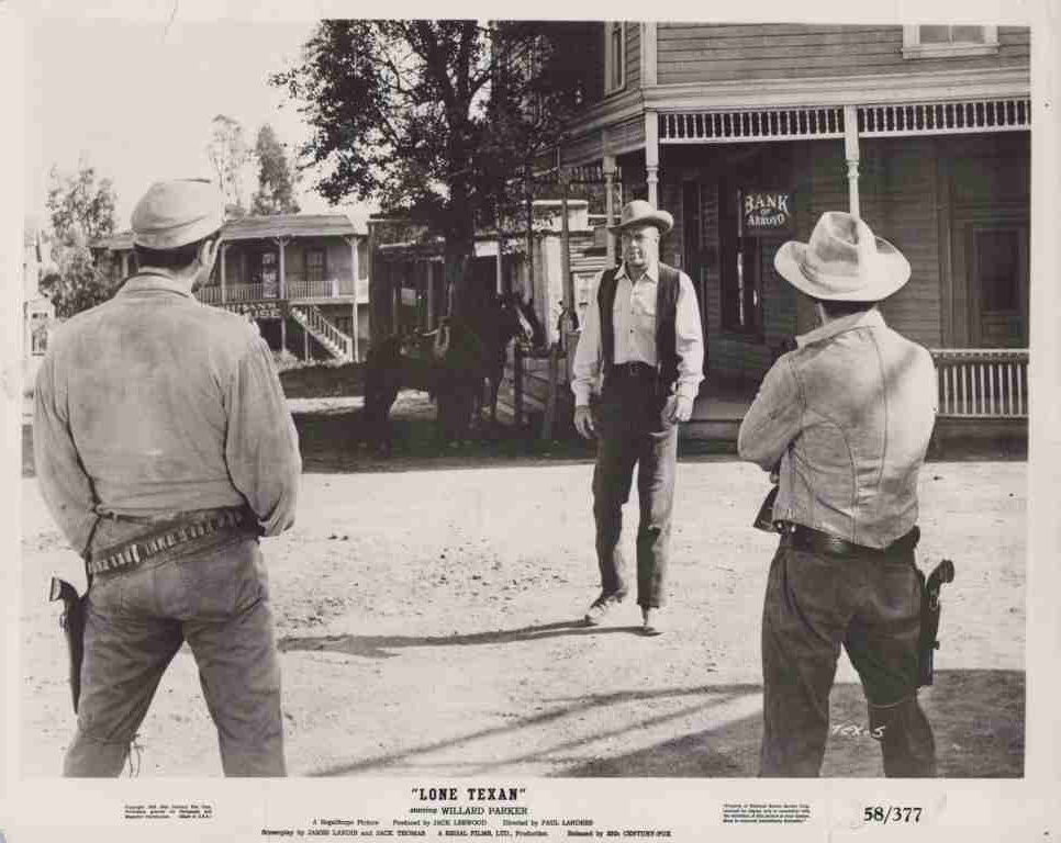 Three cowboys in a dusty Western town square; two gunfighters with holsters face a man in a hat near a bank storefront.