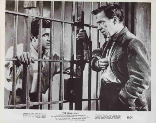 Two men separated by jail bars in a black-and-white film still; one outside in a suit confronts a prisoner inside the cell (The Long Rope).
