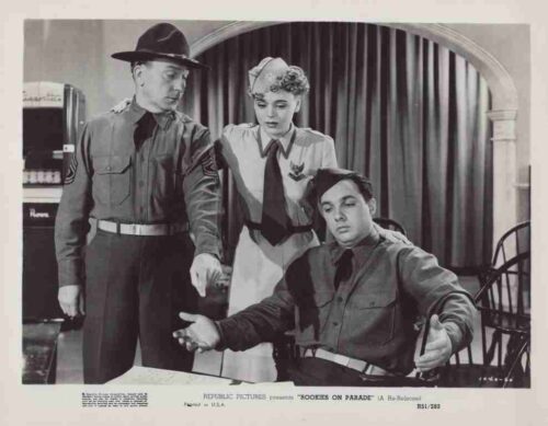Black-and-white film still of two soldiers and a woman in uniform with a seated man in a chair, from the 1940s-era film 'Rookies on Parade' (publicity image).