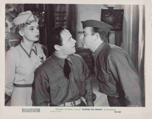 Two men in military uniforms lean toward each other as a nurse watches in a vintage scene.